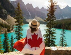 אישה עם דגל קנדה עומדת מול אגם
